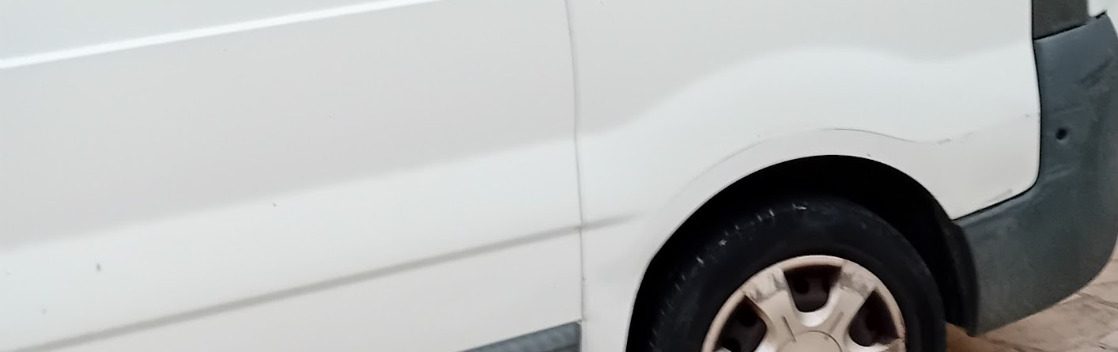 fourgon Fourgon blanc avec une roue visible et un bas de caisse gris.